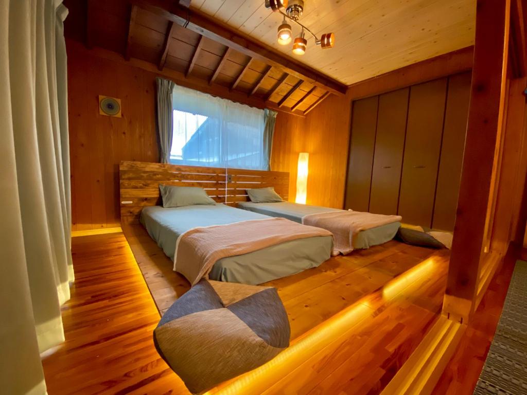 Un dormitorio con dos camas y una ventana. en 奄美 大和宿 AMAMI yamato INN, 