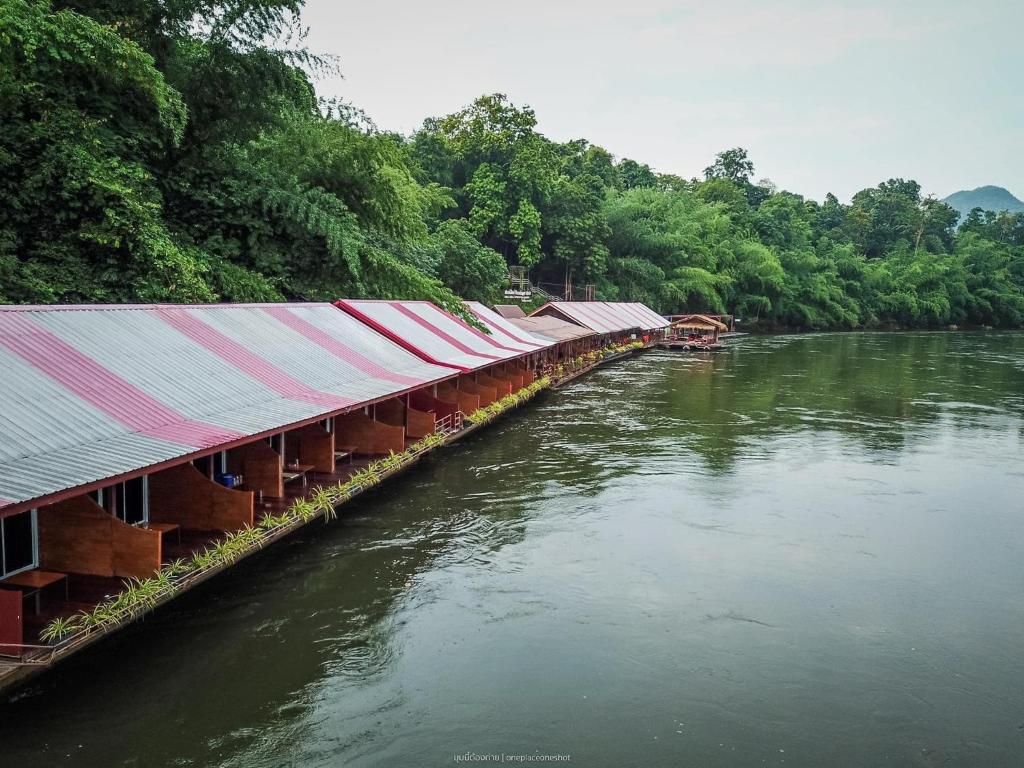 eine Reihe von Gebäuden auf einem Fluss neben Bäumen in der Unterkunft Star Hill River Kwai Resort in Ban Kaeng Raboet