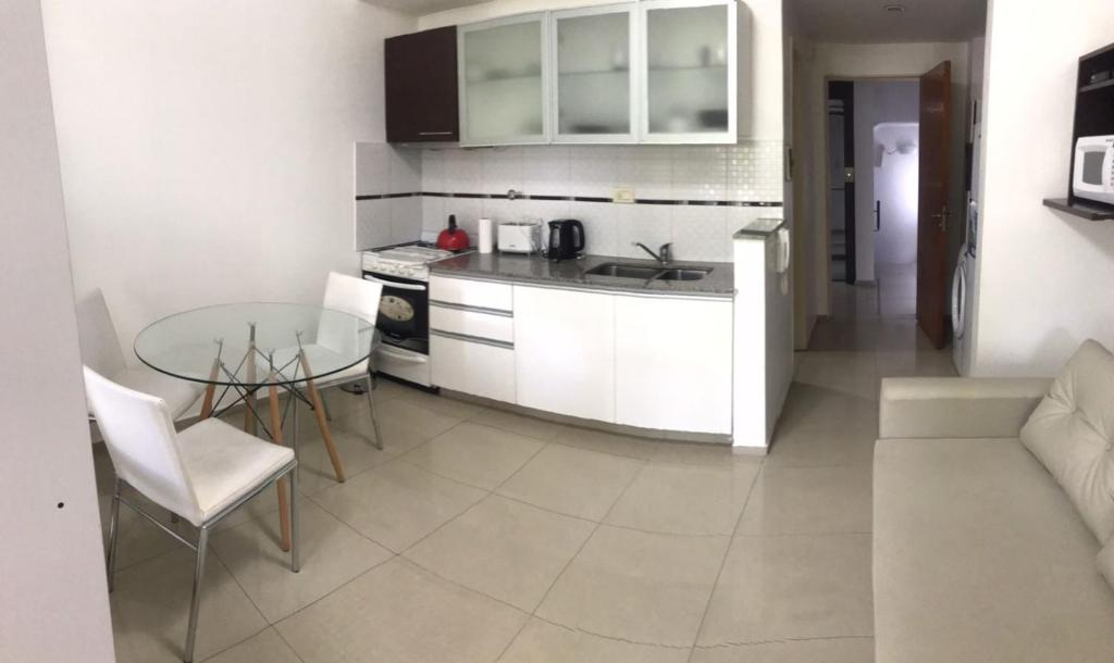 cocina con armarios blancos y mesa de cristal en Loft Espectacular Céntrico con Garaje en Rosario