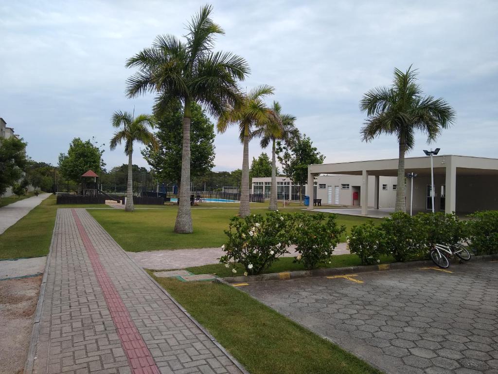 a building with palm trees in front of a park at Condomínio Ilha do Sol in Florianópolis