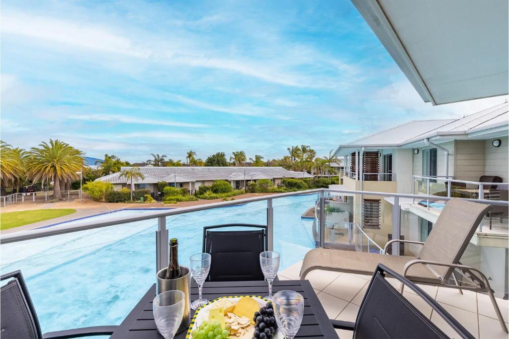 a table with a plate of food on a balcony with a pool at Pacific Blue 278-265 Sandy Pt Rd- Dual Key Access, Wifi, Linen and Air Conditioning in Salamander Bay