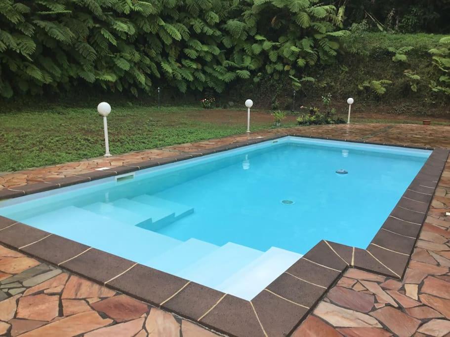 una piscina de agua azul en un patio en Les Lucioles 2 Beau T3 en forêt tropicale avec piscine, en Saint-Joseph