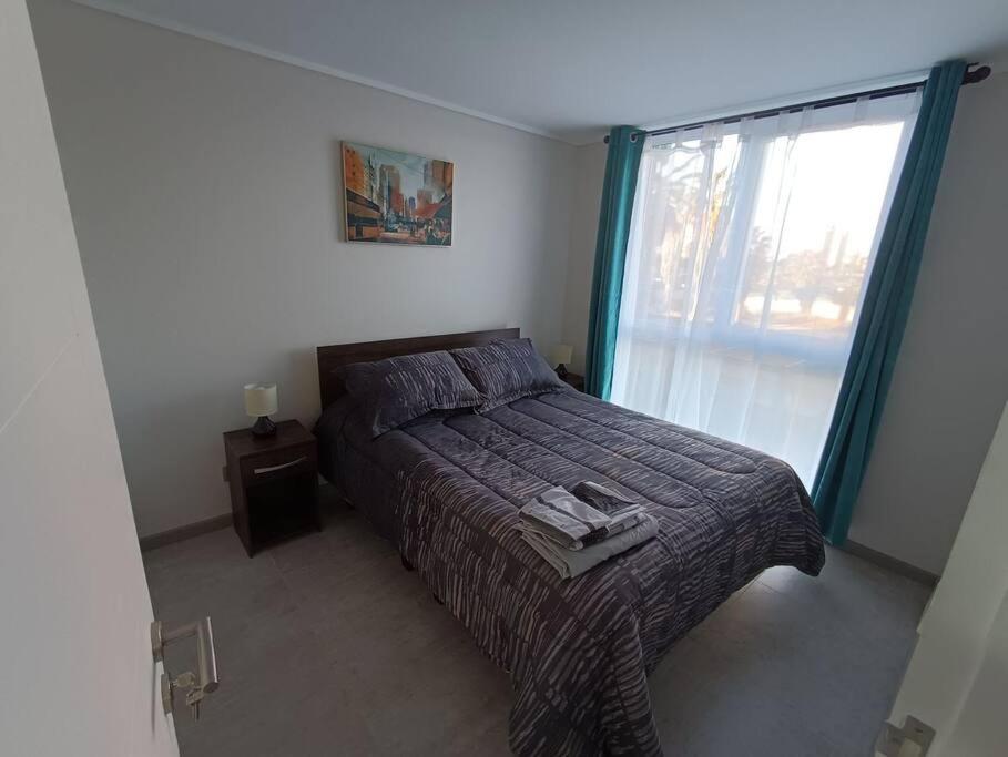 a bedroom with a bed and a large window at La herradura departamento nuevo a pasos de la playa 2 dorm 1 baño in Coquimbo