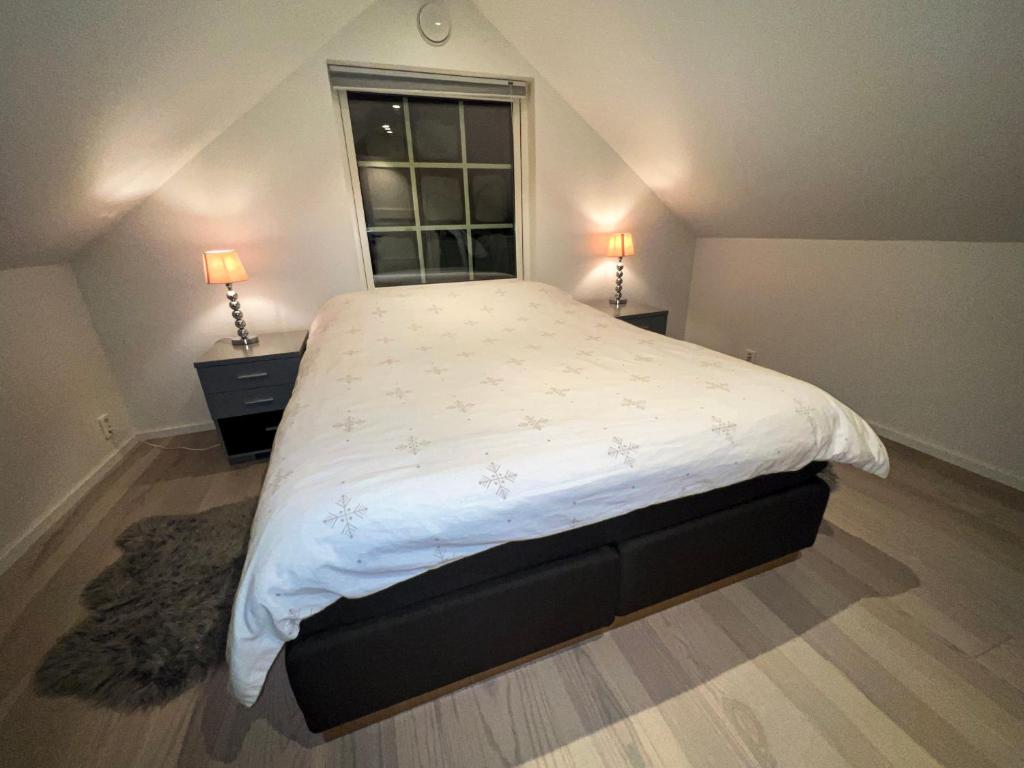 a bedroom with a large bed with two night stands and a window at Penthouse apartment with amazing view. in Tromsø