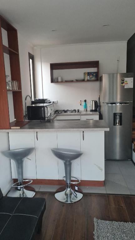 a kitchen with white cabinets and a stainless steel refrigerator at Cerca Reloj Flores Viña in Viña del Mar