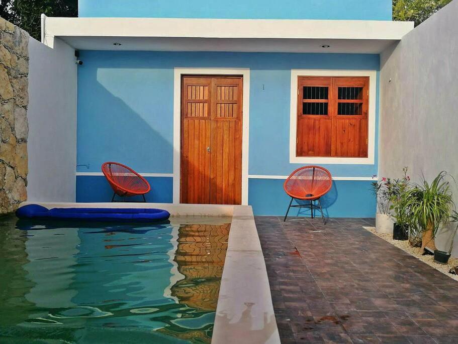 a blue house with two chairs and a swimming pool at La Conchita de Sisal 1 in Sisal