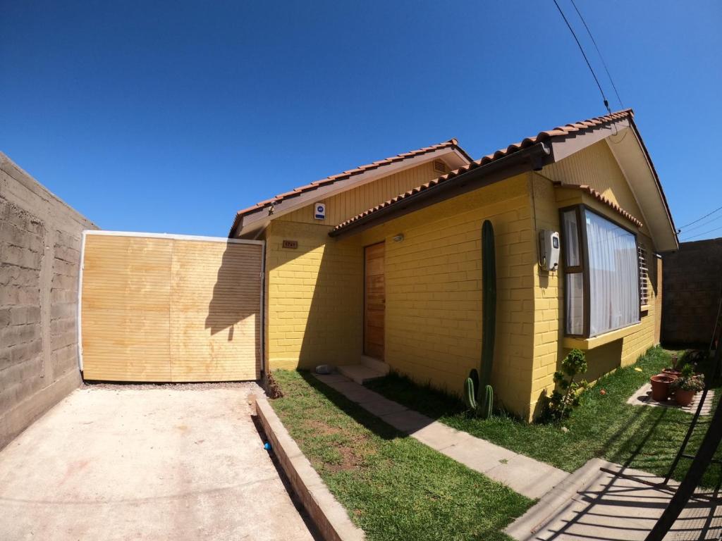 een geel huis met een hek ernaast bij My Home in La Serena