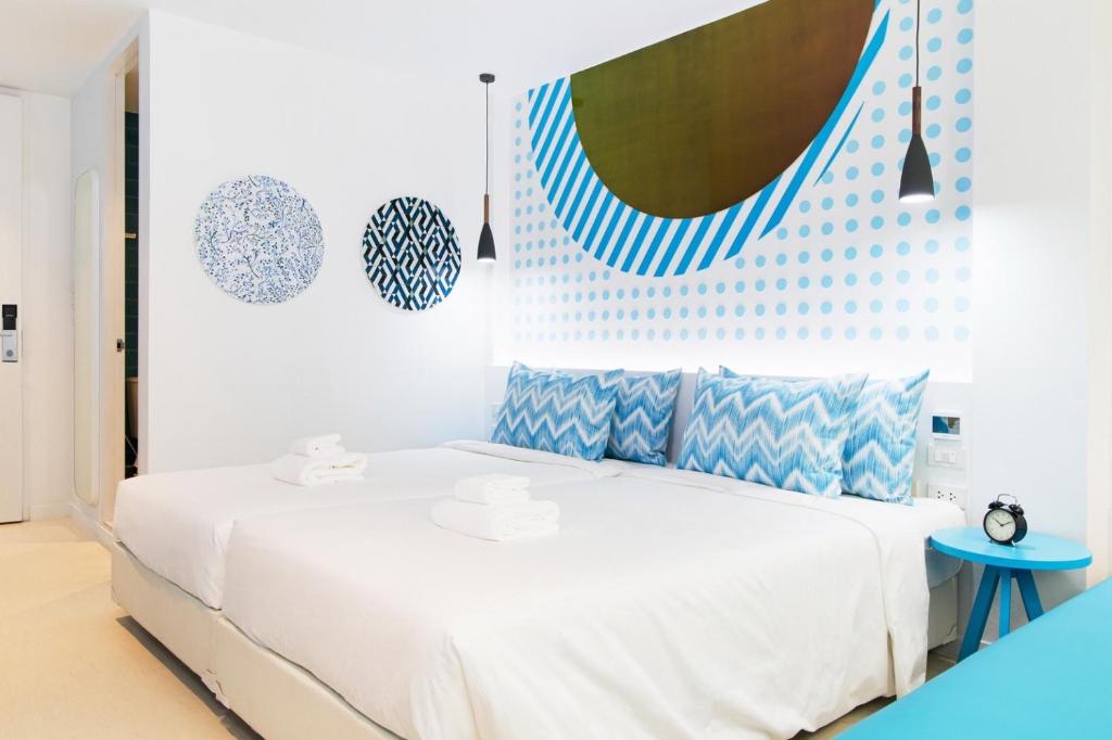 a bedroom with a white bed with blue accents at Budacco The Living Place in Bangkok