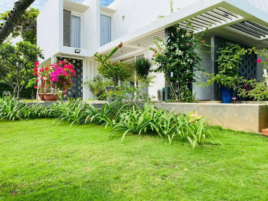 une maison avec des fleurs et des plantes dans la cour dans l'établissement Oceanami Resort - Bali Villa 4Bedrooms, 400m2, BBQ, à Long Hải