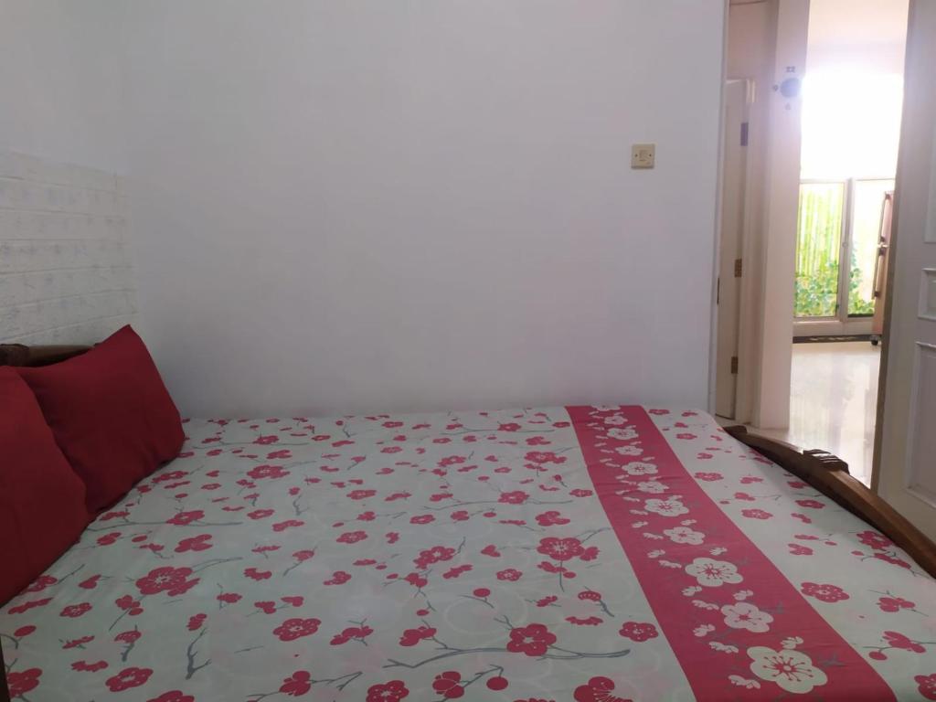 a bedroom with a bed with a floral blanket on it at D5 Homestay Syariah Sumampir Purwokerto in Purwokerto