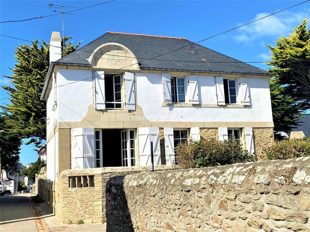 ein weißes Haus hinter einer Steinmauer in der Unterkunft Villa Quiberon, 5 pièces, 8 personnes - FR-1-478-170 in Quiberon