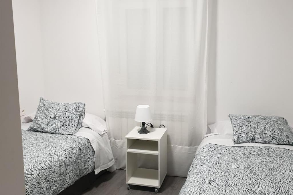 a bedroom with two beds and a lamp on a night stand at Logroño Centro Home in Logroño