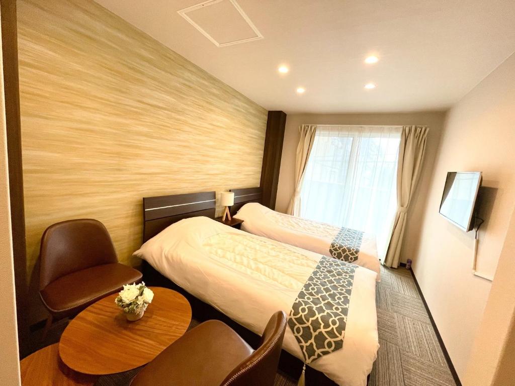 winco - Vacation STAY 06648v في طوكيو: غرفة فندقية بسريرين وطاولة وكراسي