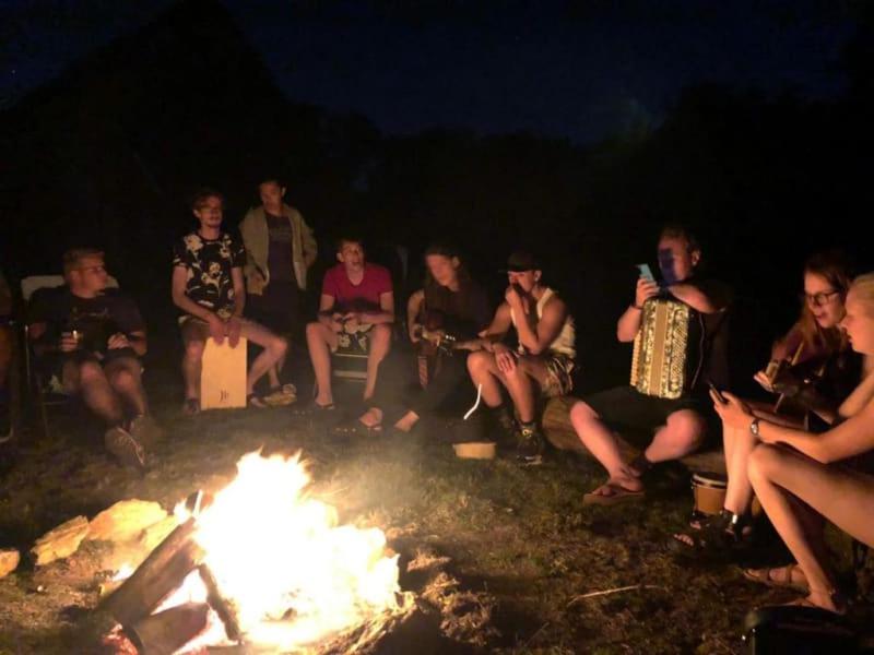grupa ludzi siedzących przy ogniu w obiekcie Camping La cour d'Enchère w mieście Saint-Palais