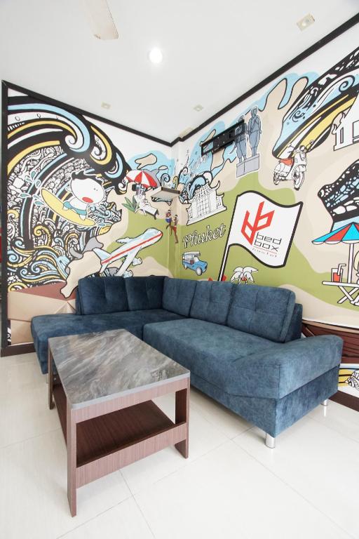 a living room with a couch and a mural at Bedbox Hostel in Patong Beach