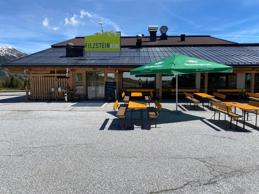 ein Restaurant mit Tischen, Stühlen und einem Sonnenschirm in der Unterkunft Apartments Filzsteinalm, Hochkrimml in Kirchdorf