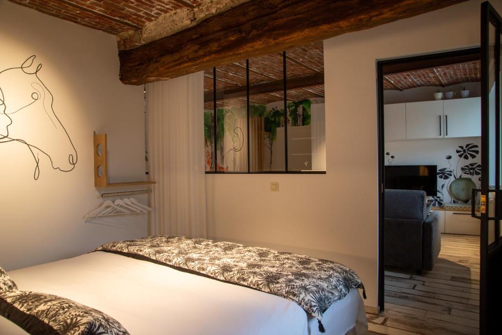 Le Relais de la Posterie في جيمبلو: غرفة نوم مع سرير وغرفة معيشة