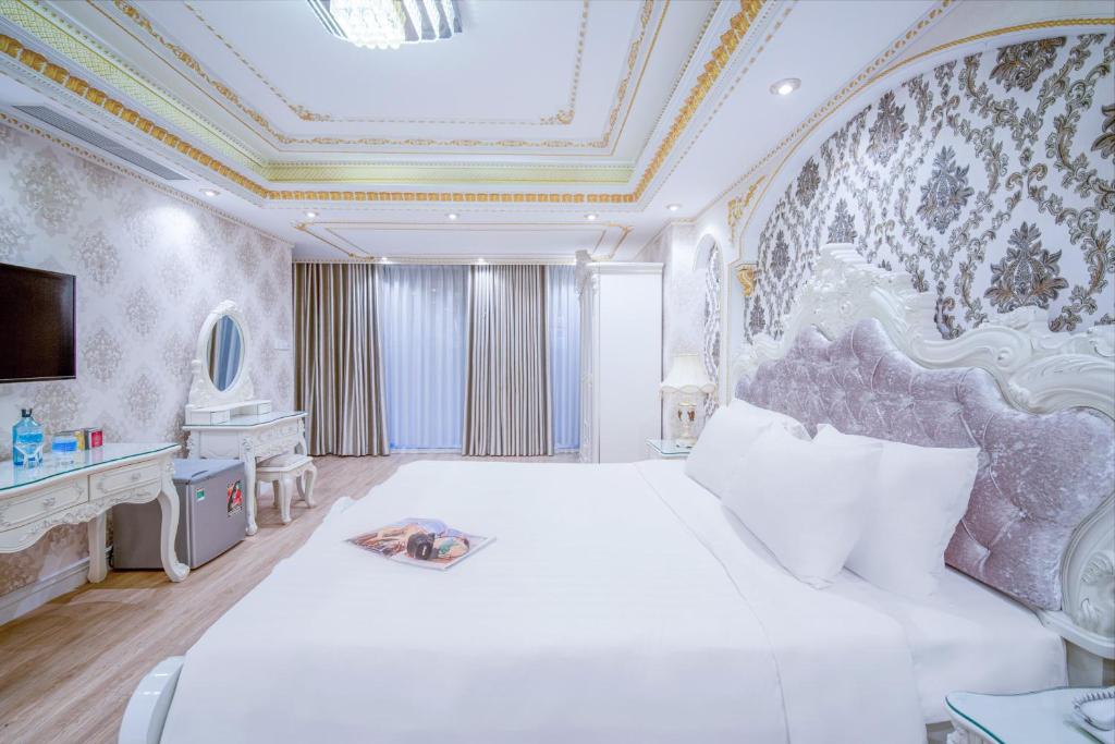 een slaapkamer met een groot wit bed en een mooi plafond bij Royal Beach Hotel by THG in Da Nang