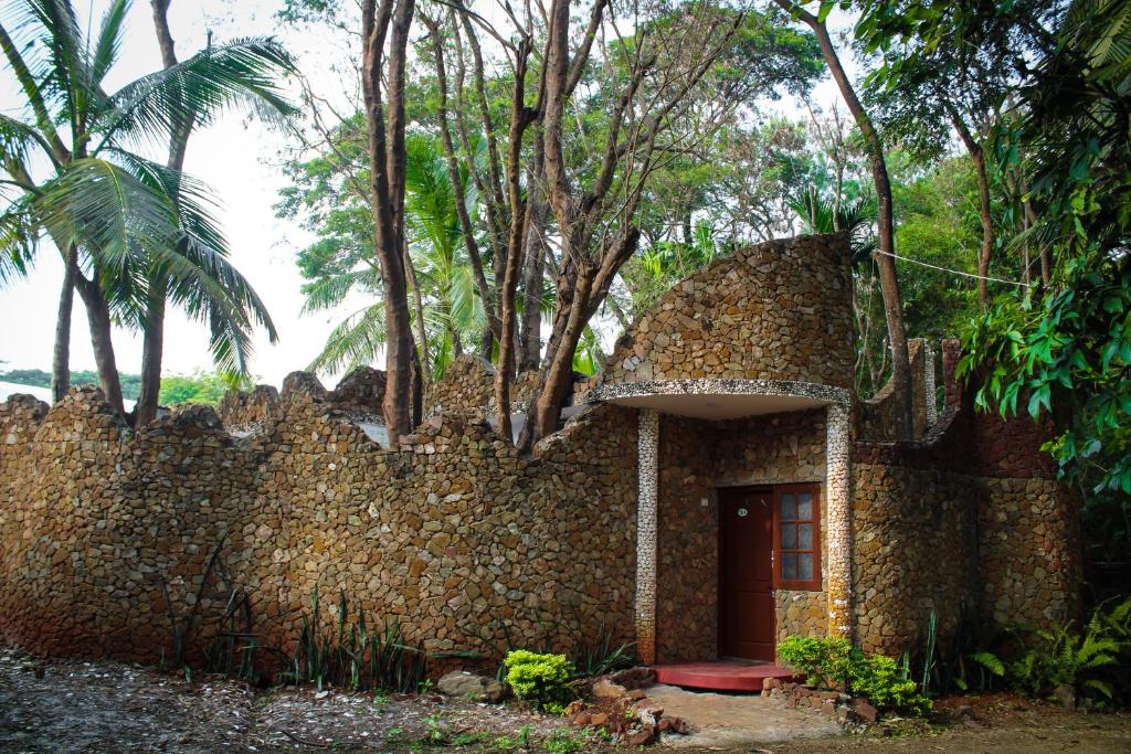 una vecchia casa in pietra con un muro e una porta di Advaitha Serenity Resorts a Kālvādi