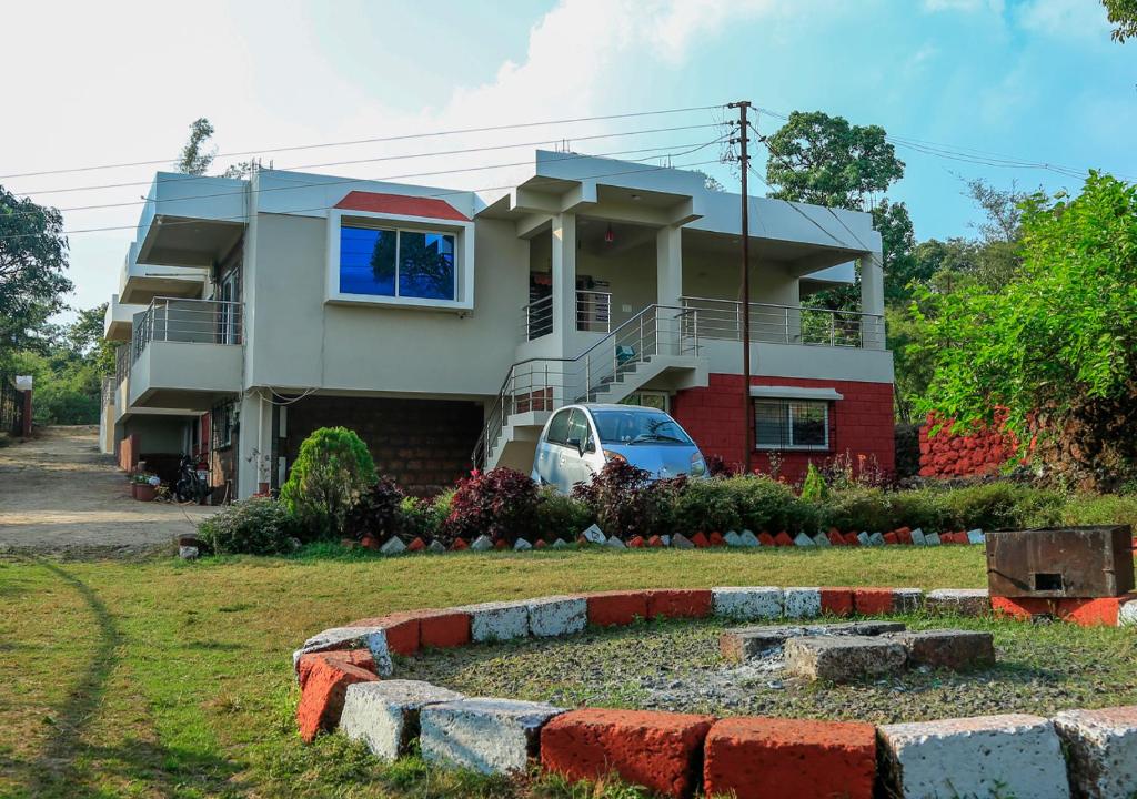una casa con un coche aparcado delante de ella en Shriyan Farmhouse Mahabaleshwar, en Mahabaleshwar