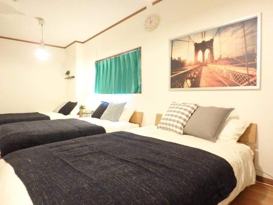 a bedroom with three beds and a painting on the wall at Dotonbori Mansion 401 in Osaka