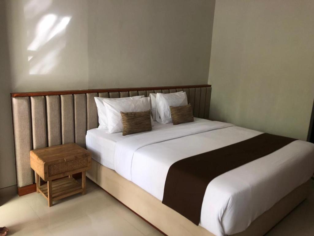 una camera da letto con un grande letto con lenzuola e cuscini bianchi di Dewi Dewi Villas a Sanur