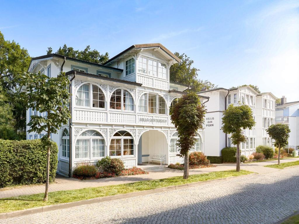 una grande casa bianca con alberi di fronte di Villa am Park a Binz