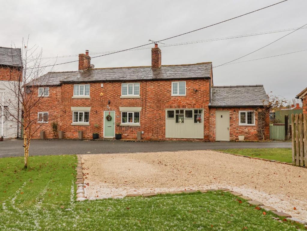 una casa de ladrillo rojo con garaje blanco en Mill Lane Cottage, en Chester