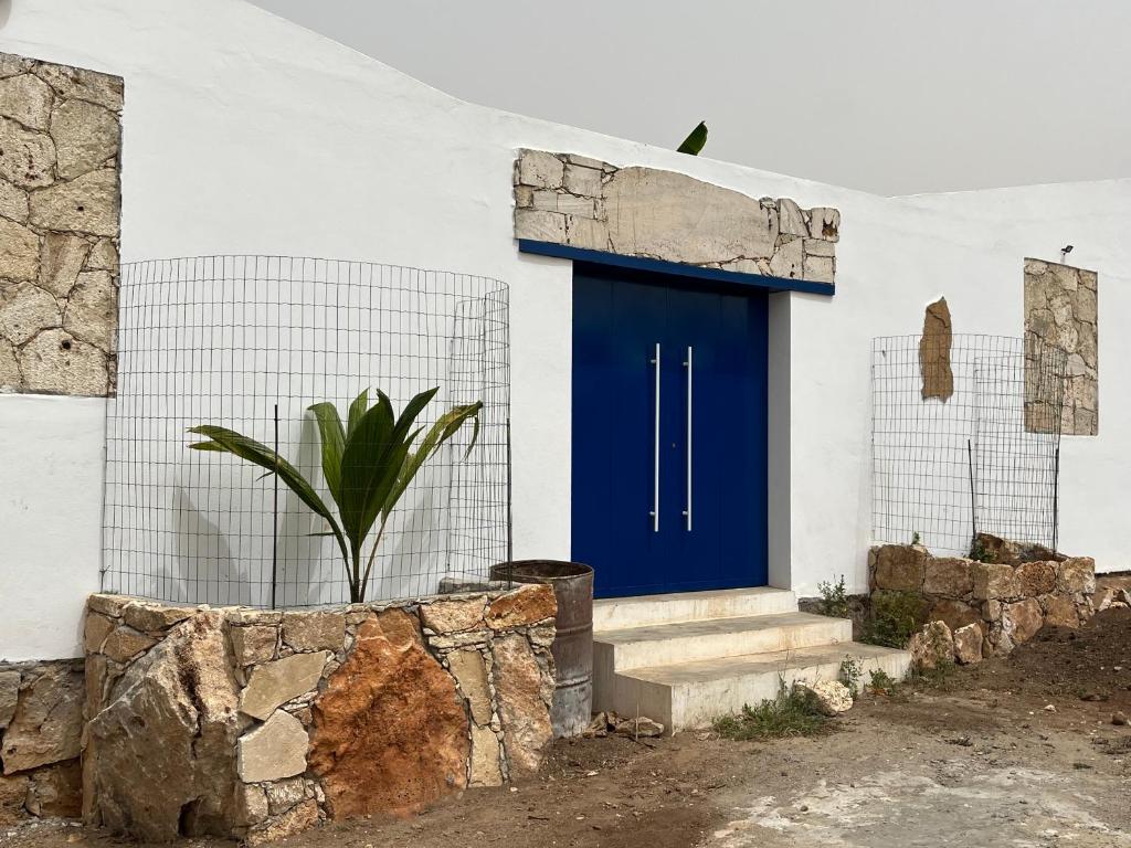 a blue door on the side of a white building at Quintal do Maio in Vila do Porto