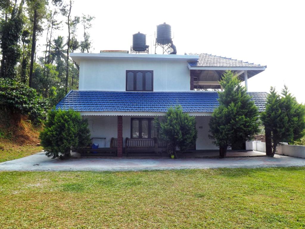 a white house with a blue roof at Sandev Homestay in Madikeri