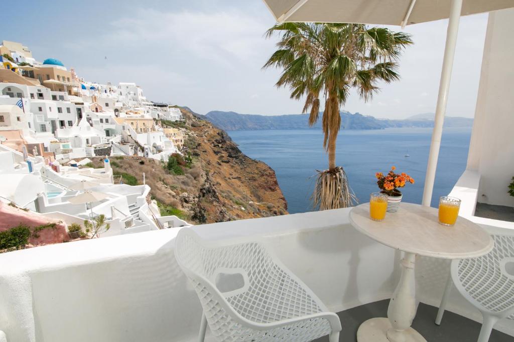 a table and chairs on a balcony with a view of the ocean at Vogue Suites in Oia