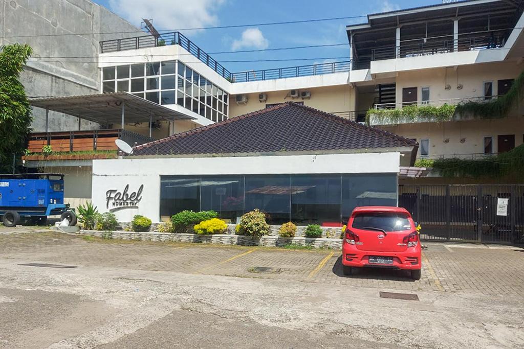 a red car parked in a parking lot in front of a building at Fabel Homestay in Palembang