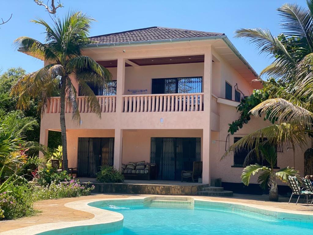 une maison avec une piscine en face de celle-ci dans l'établissement Tradewinds Lodge, à Diani Beach