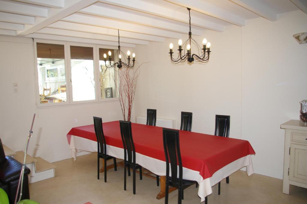 a dining room with a red table and chairs at La Cognée in Cugnaux