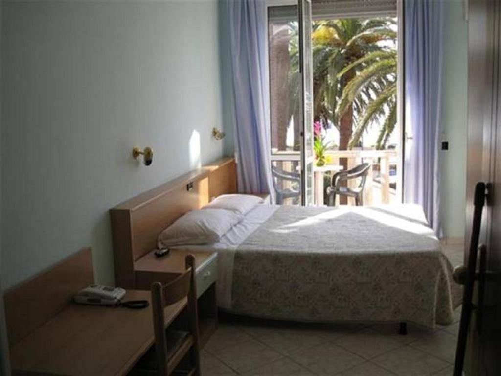 een slaapkamer met een bed, een bureau en een raam bij Hotel Corallo in Finale Ligure