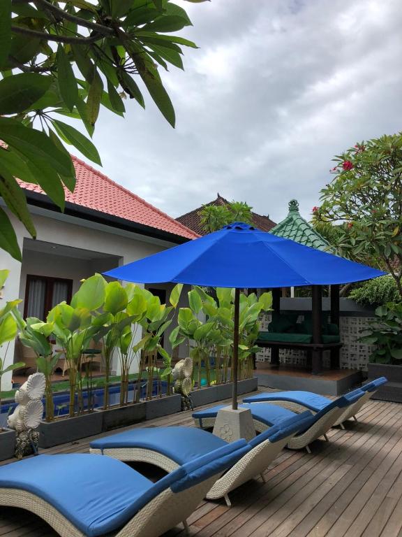 a group of chairs and an umbrella on a deck at Dewi Dewi Villas in Sanur