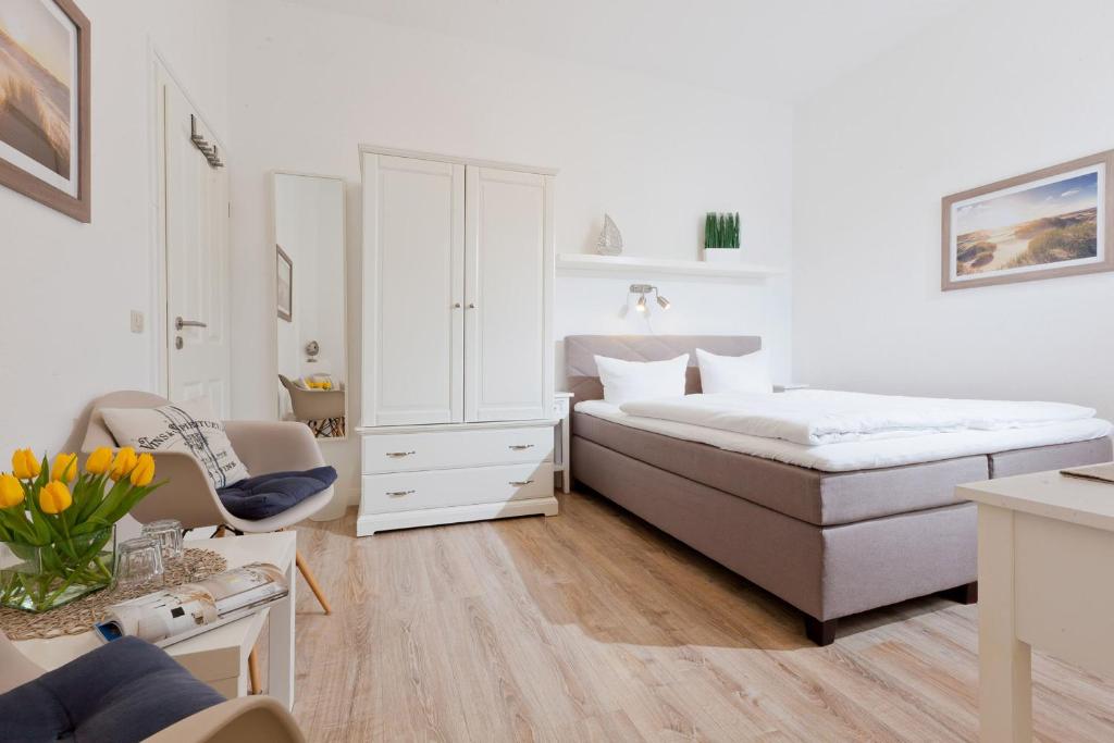 a white bedroom with a bed and a chair at Haus Menno Janssen - Doppelzimmer in Norderney