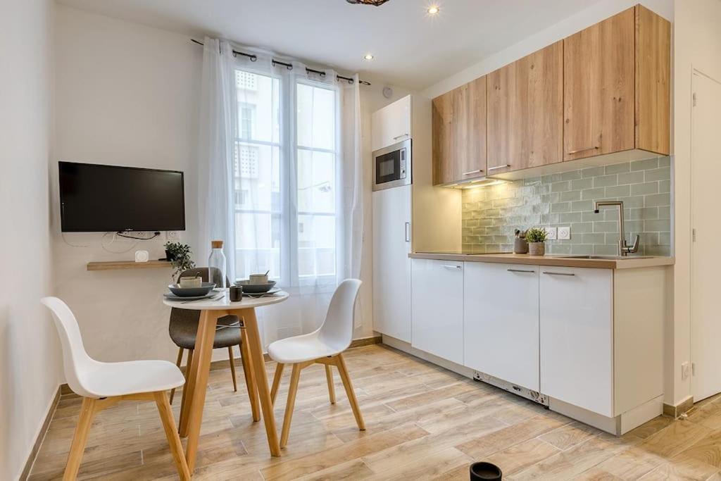 kuchnia ze stołem i białymi krzesłami oraz telewizorem w obiekcie Bel appartement aménagé de 30m2 w mieście Colombes