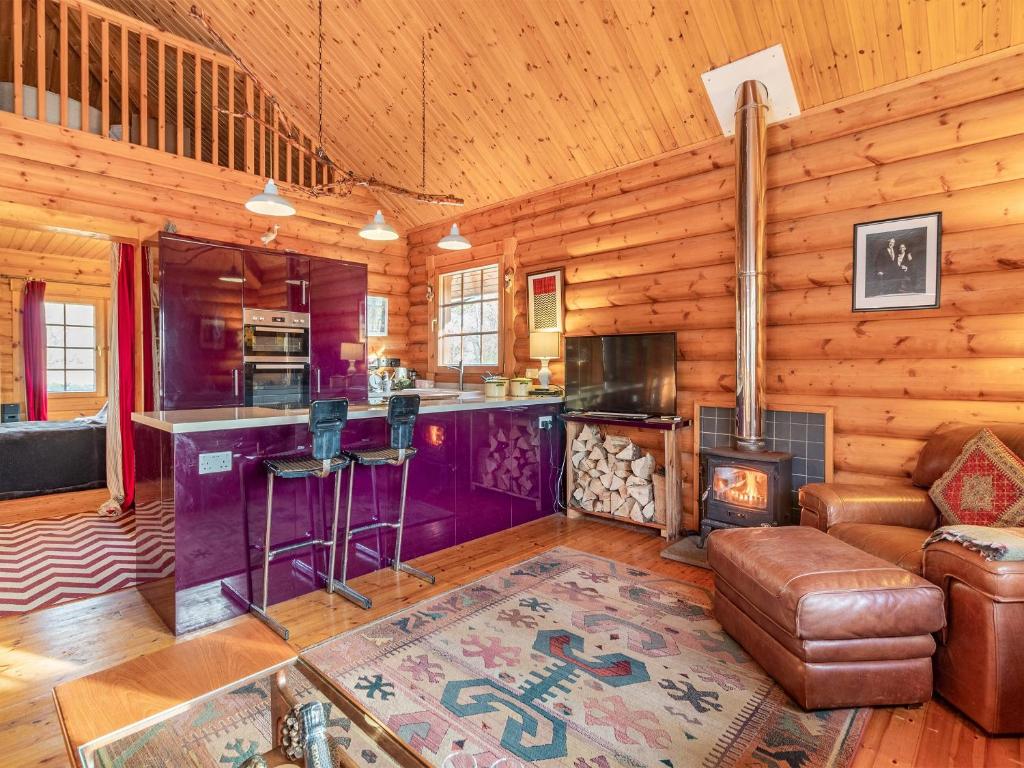 a living room with a fireplace in a log cabin at Grebe Lodge lodge 6 in Stratton Strawless