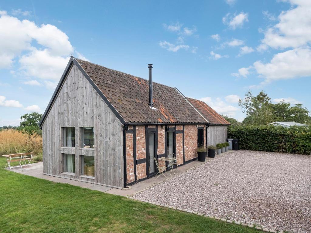 a barn style house with a gravel driveway at Green Farm Barn in Wrenbury
