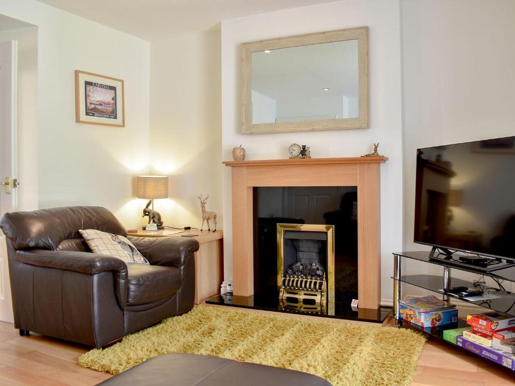 a living room with a leather chair and a fireplace at Ivy Cottage in Warwick