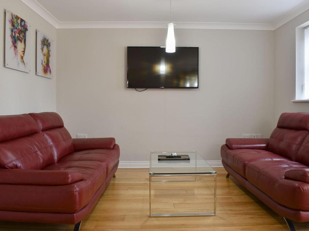 a living room with two red couches and a tv at Hollies Cottage 9 - Ukc4532 in Martock