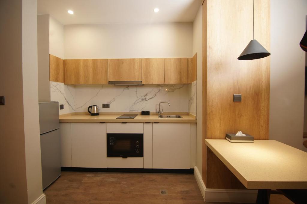 a kitchen with white cabinets and a sink and a table at Loft Hotel Apartment in Addis Ababa