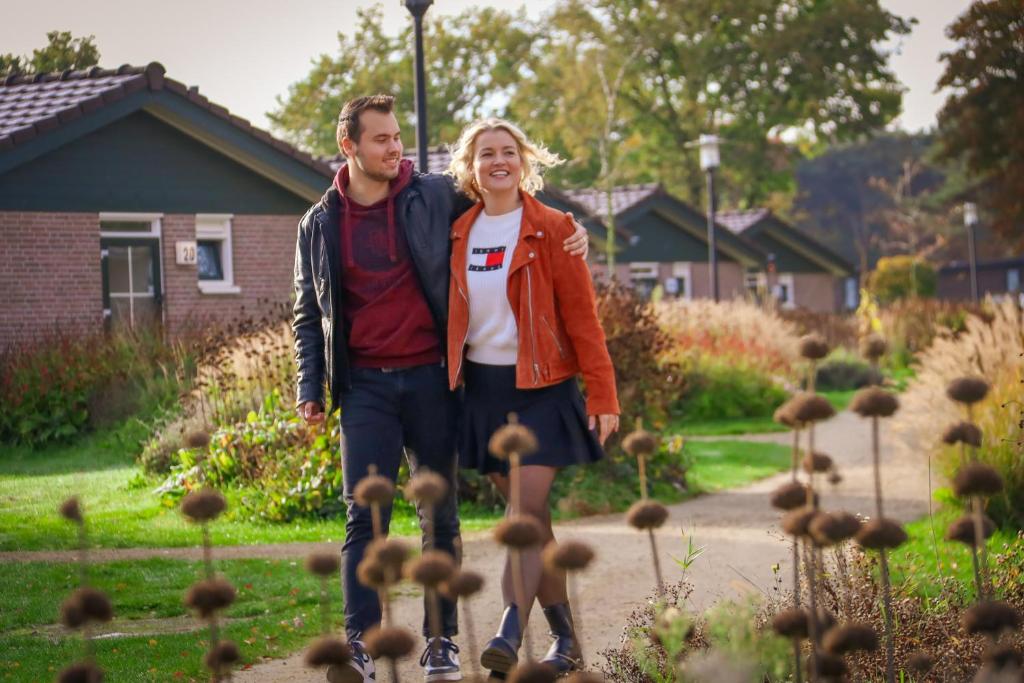 um homem e uma mulher em pé num jardim em Vakantiepark De Boshoek em Voorthuizen