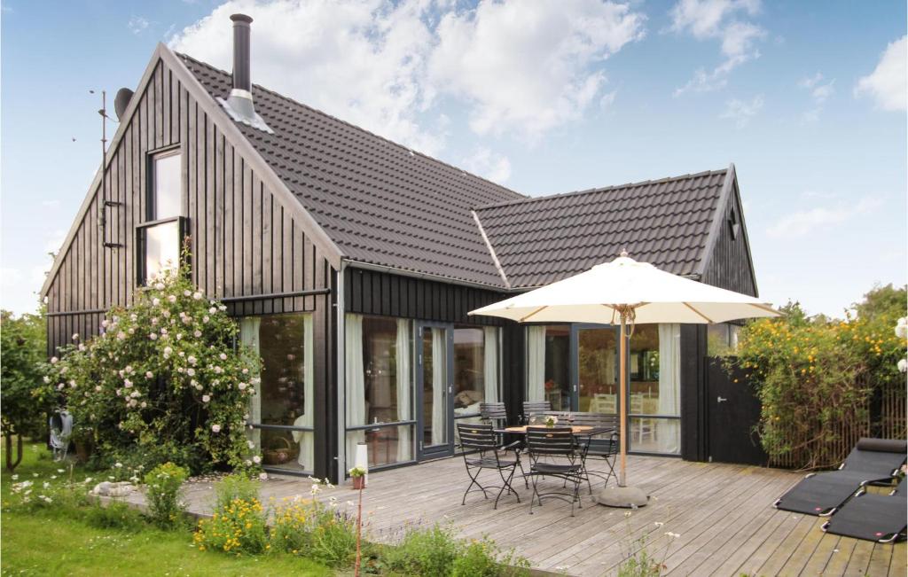 ein Haus mit einer Holzterrasse und einem Sonnenschirm in der Unterkunft Beautiful Home In Sams With Kitchen in Nordby