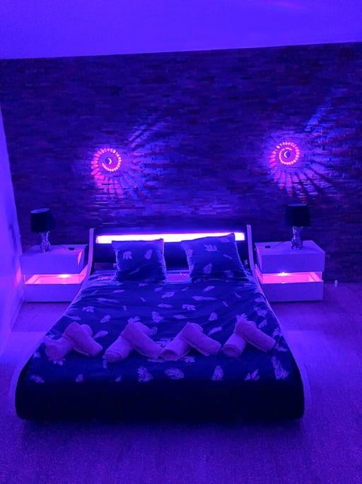 a purple bedroom with a bed with purple lights at La marbrière, Parking gratuit, proche centre ville in Sens