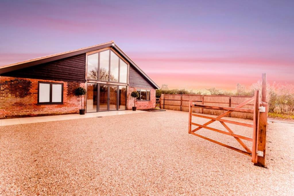 a house with a fence and a barn at Beautiful Barn Conversion Close To The Broads in Dilham