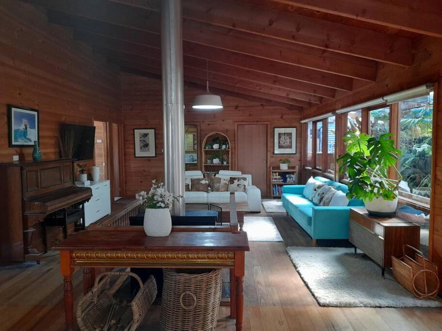 a living room with a blue couch and a piano at Bells Beach Family Retreat in Bellbrae