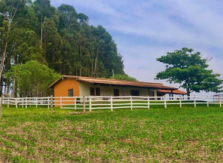 uma casa num campo com uma cerca branca em Pesqueiro Rancho Feliz em Fama