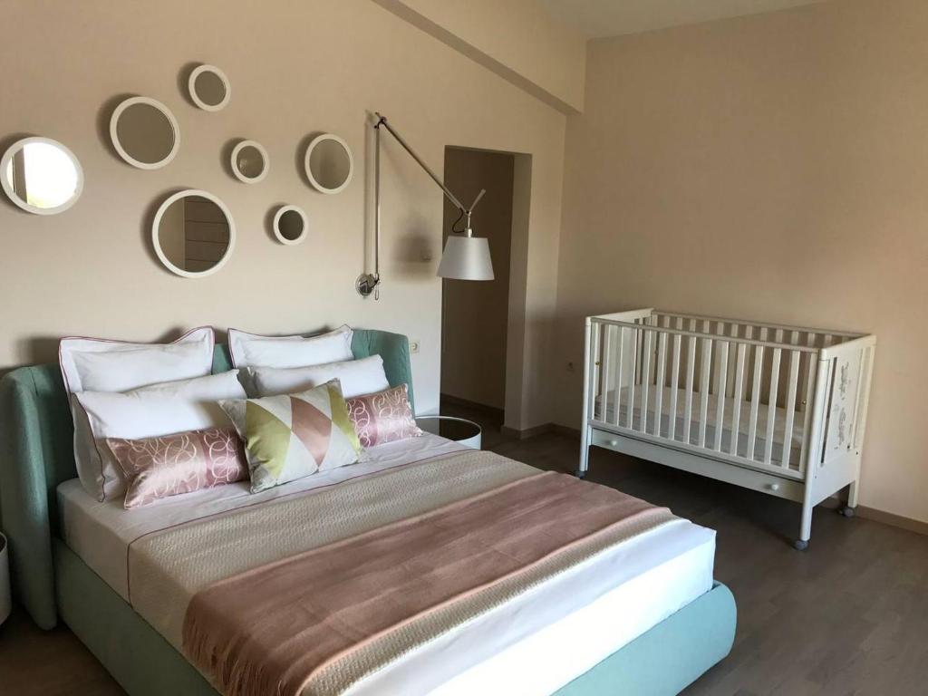 ein Schlafzimmer mit einem Kinderbett und einem Bett mit Kissen in der Unterkunft Villa Julianna in Loutraki